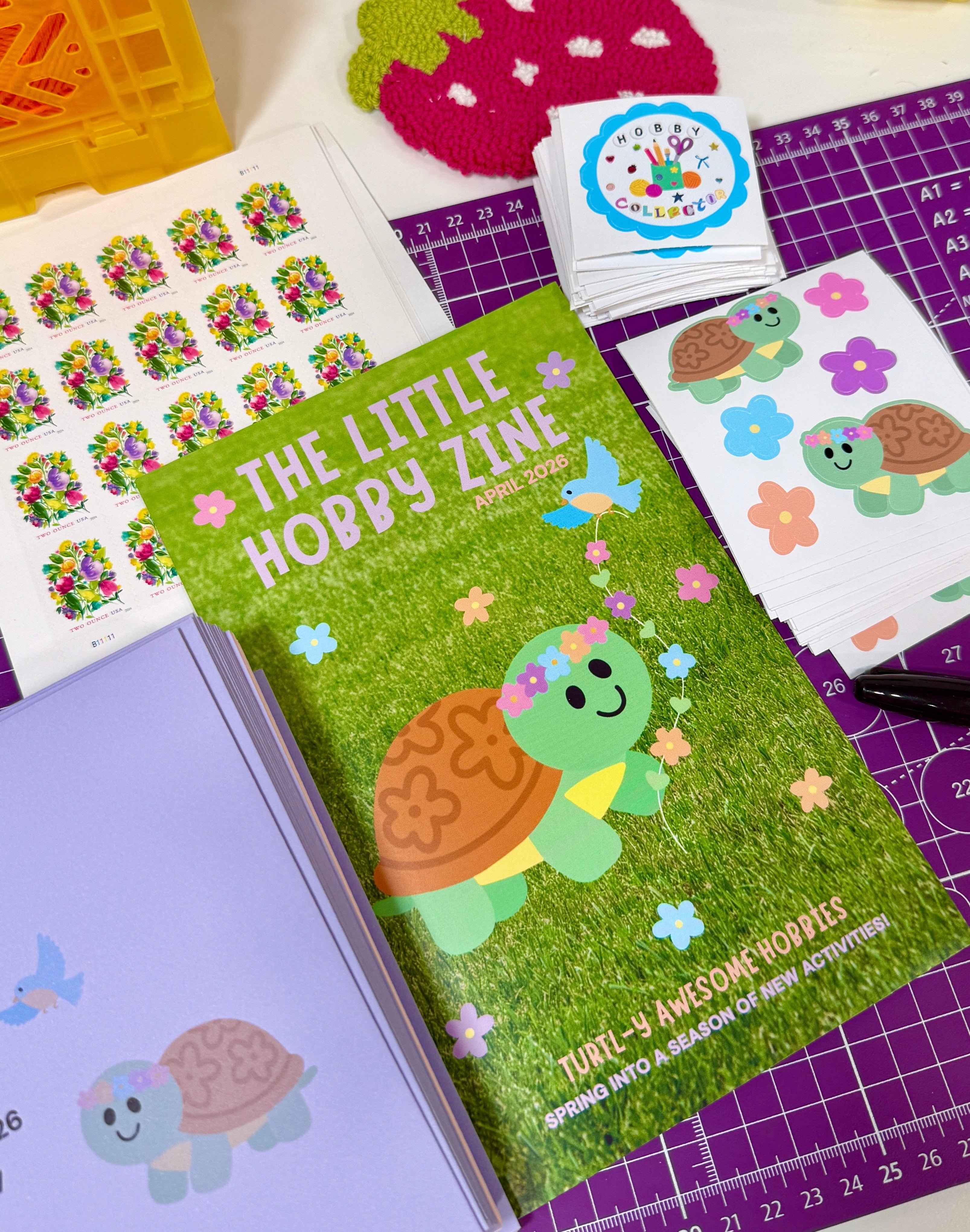 Mini magazine titled 'The Little Hobby Zine' with turtle illustration on a table with stationery items.