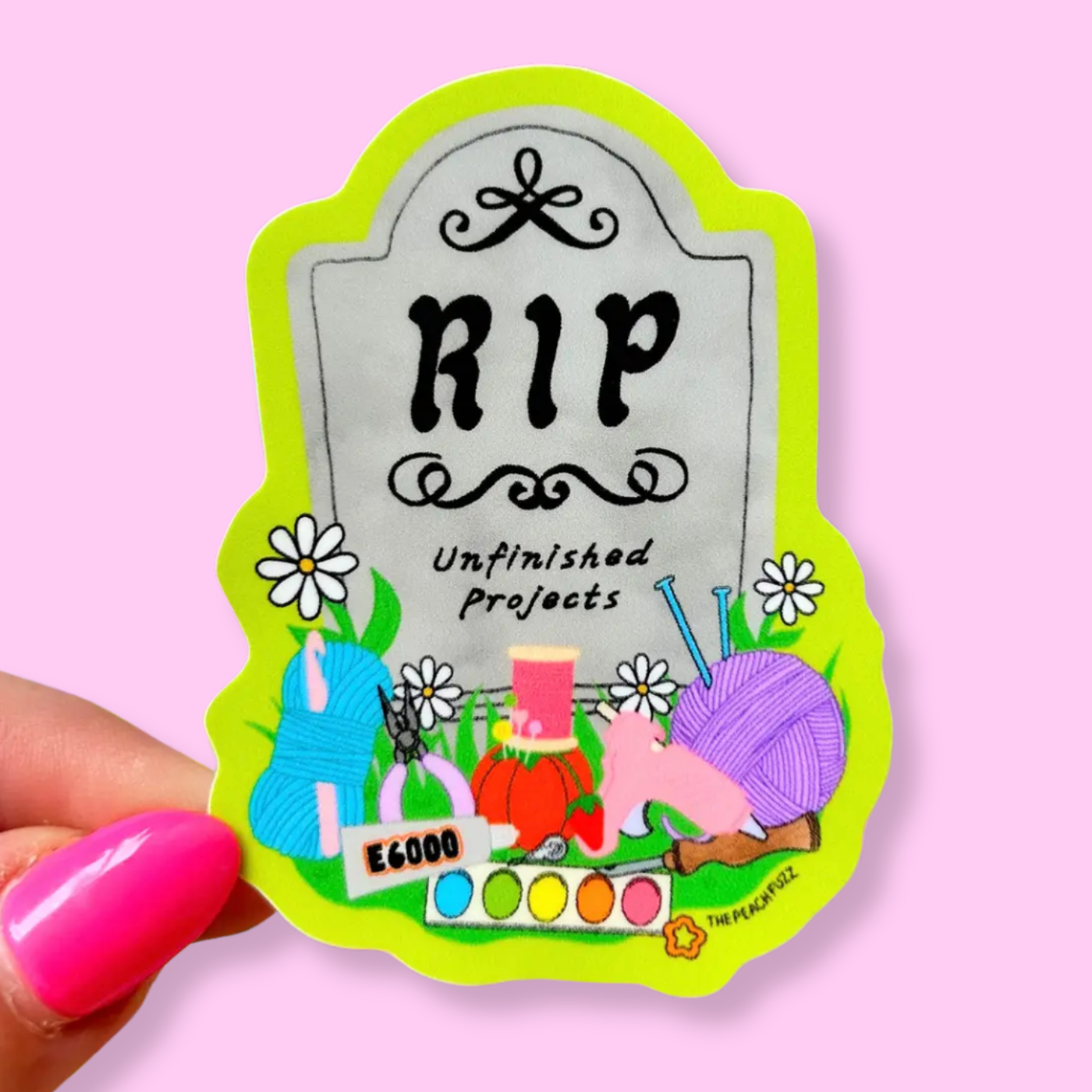A sticker with the text 'R.I.P. unfinished projects' on a gravestone surrounded by craft supplies.
