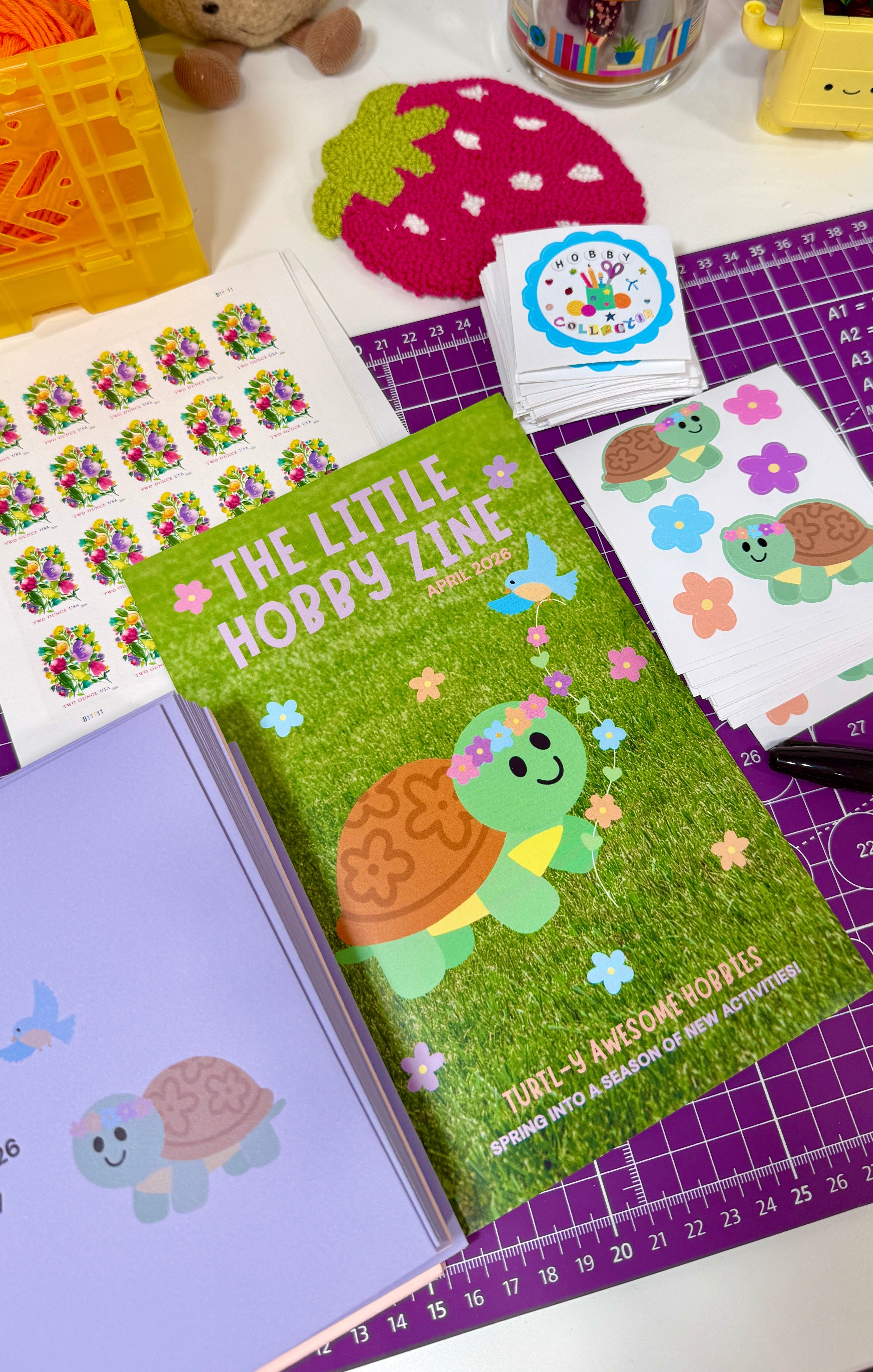 Mini magazine titled 'The Little Hobby Zine' with turtle illustration on a table with stationery items.