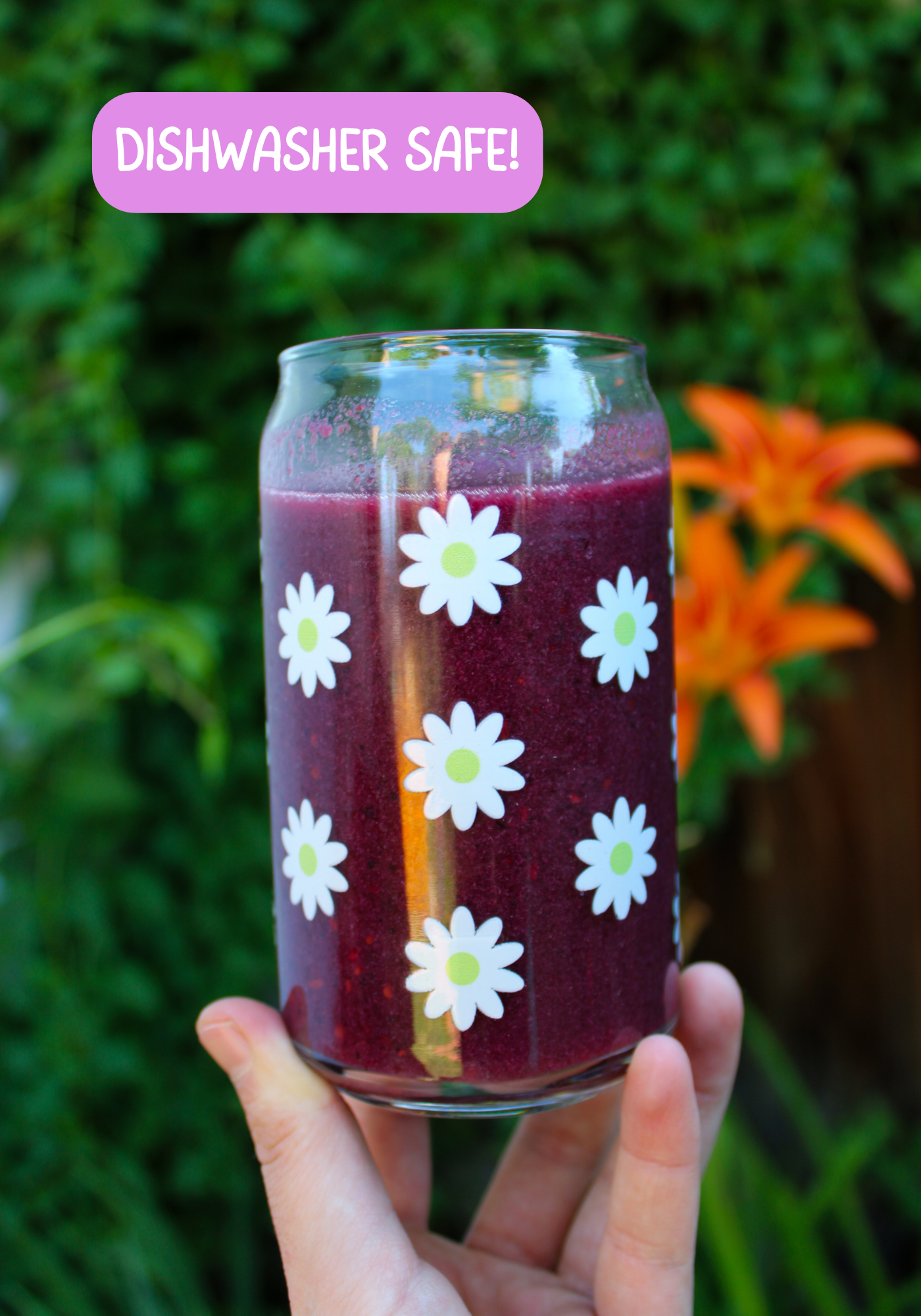 Hand holding glass can with scattered white daisies in front of a blurry plant background