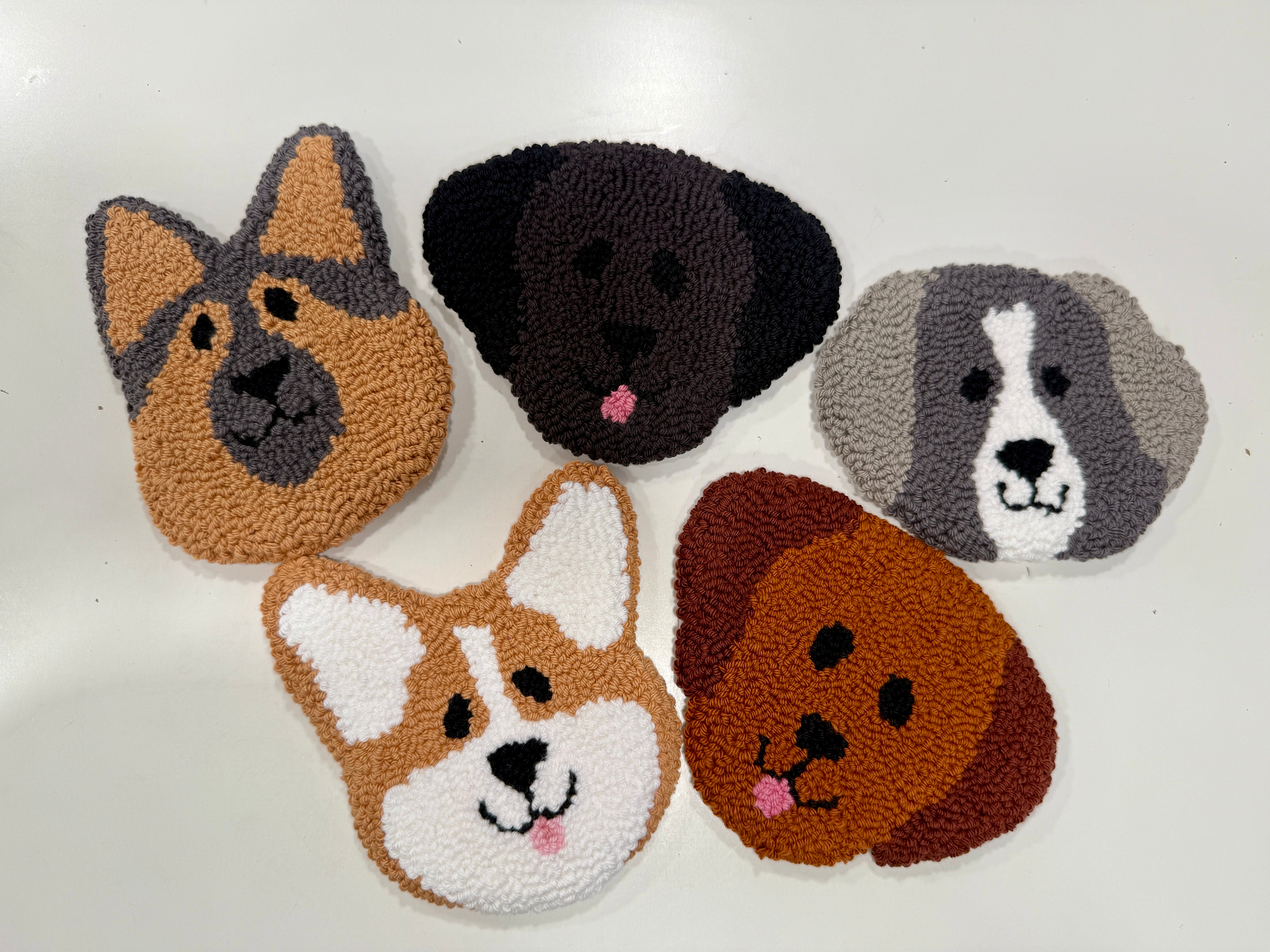 Five dog-shaped punch needle coasters with different breeds on a white background