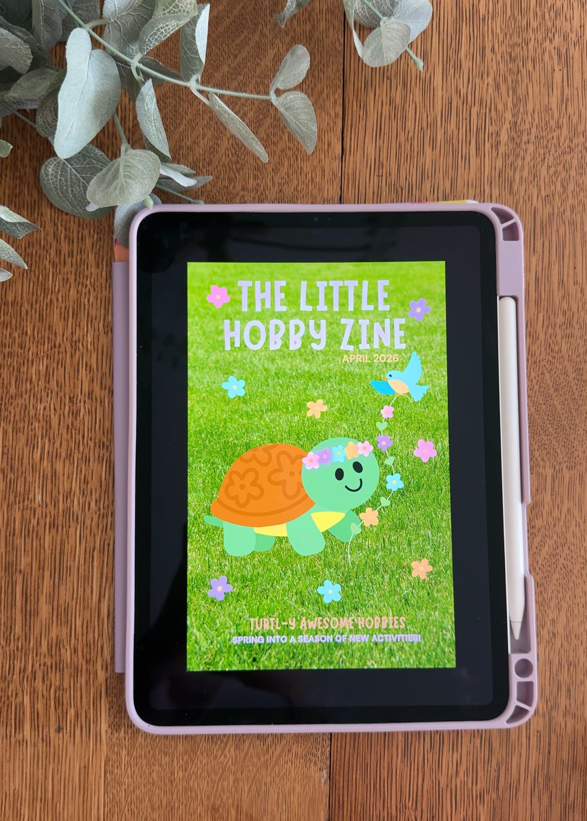 Tablet displaying 'The Little Hobby Zine' on a wooden surface with decorative elements.