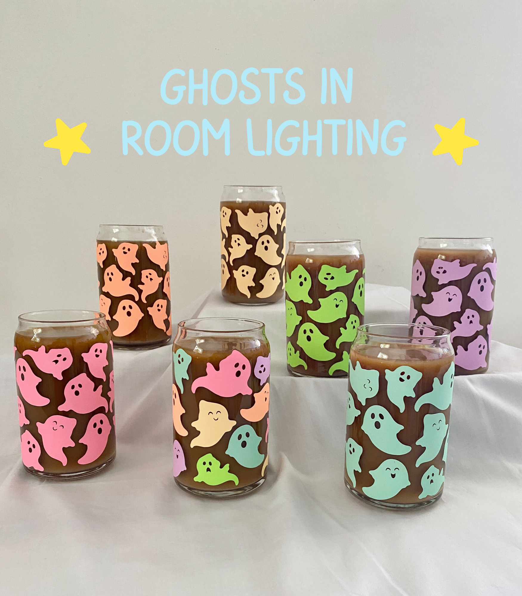 Glass cans sitting on a white sheet and filled with coffee, covered in pastel ghost design.